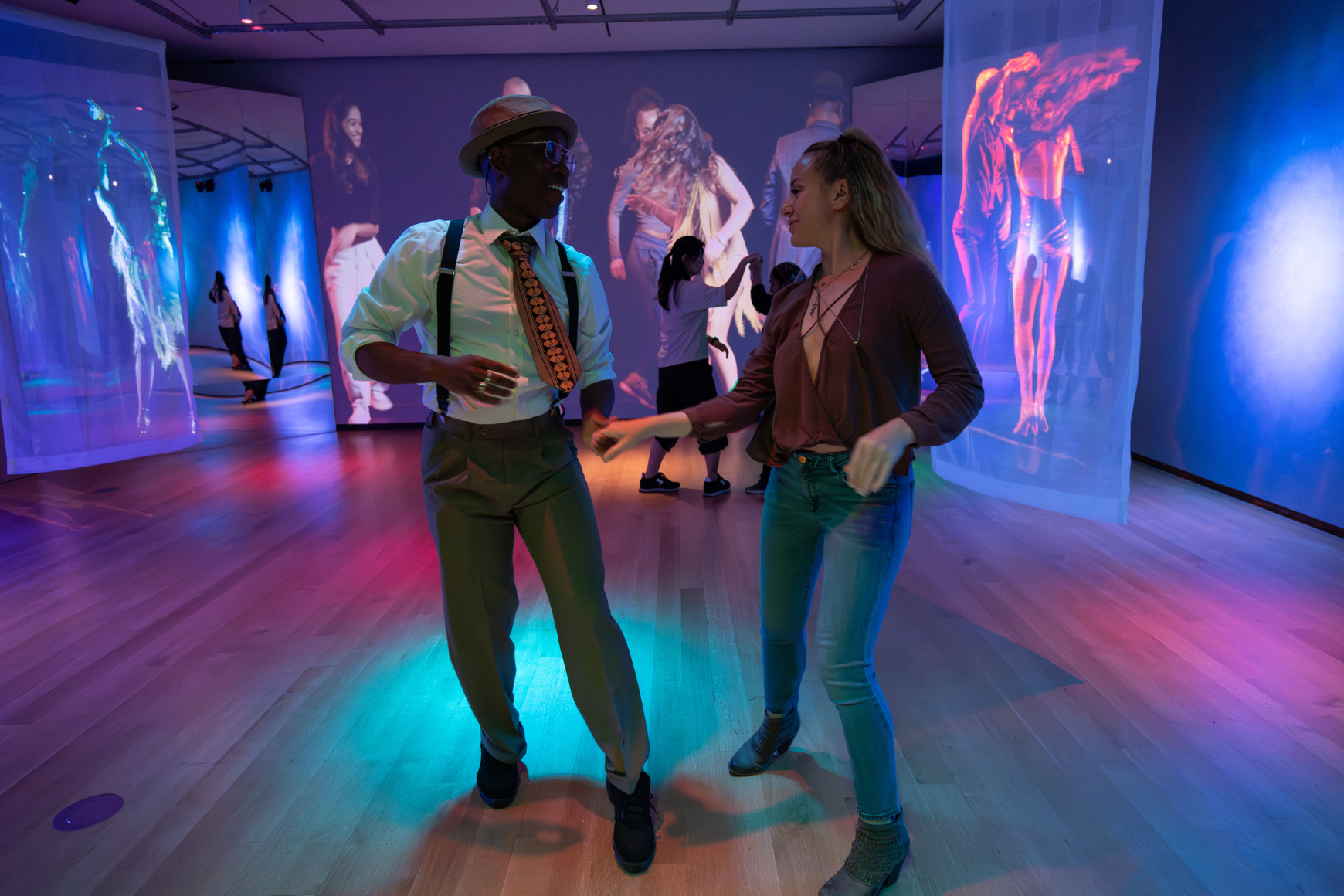 A man and woman smiling and dancing together on a disco dance floor
